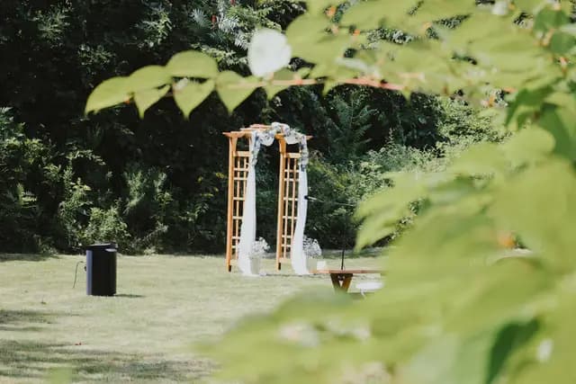 Wooden ceremony arch draped in white fabric set up in a garden