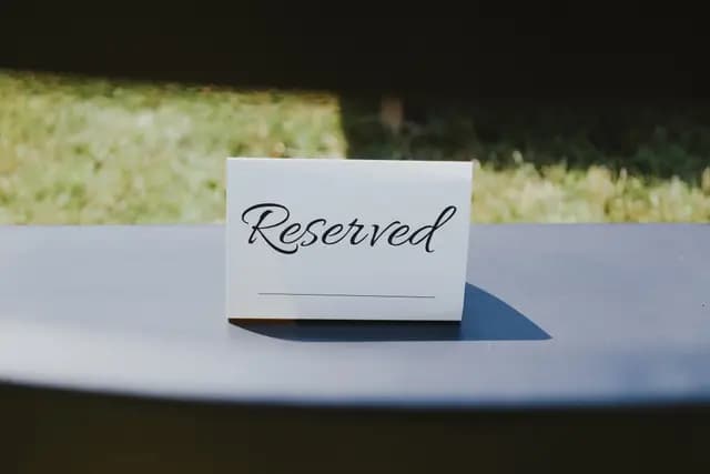 Handwritten 'Reserved' place card on a table at an outdoor wedding