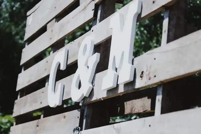 White 'C & M' initials mounted on a rustic wood pallet backdrop
