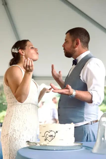 Bride and groom share a playful moment over their initialed wedding cake