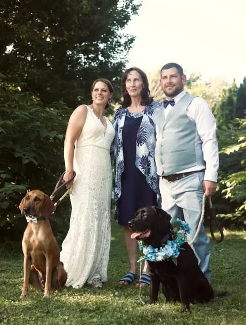 Bride, groom, and a family member pose with their two dogs