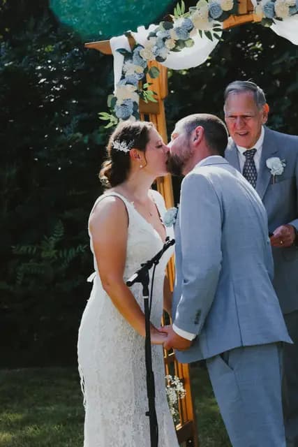 Newlyweds kiss at the altar as the officiant looks on