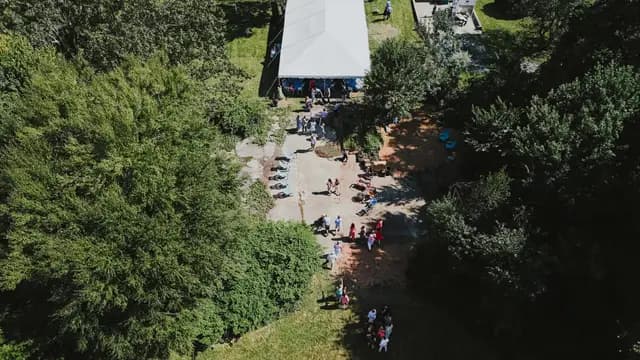 Aerial view of the white reception tent and guests among the trees