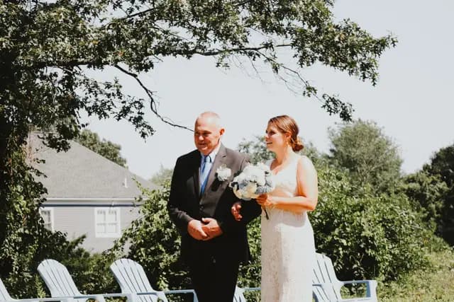 Bride is escorted along the aisle holding her bouquet before the ceremony