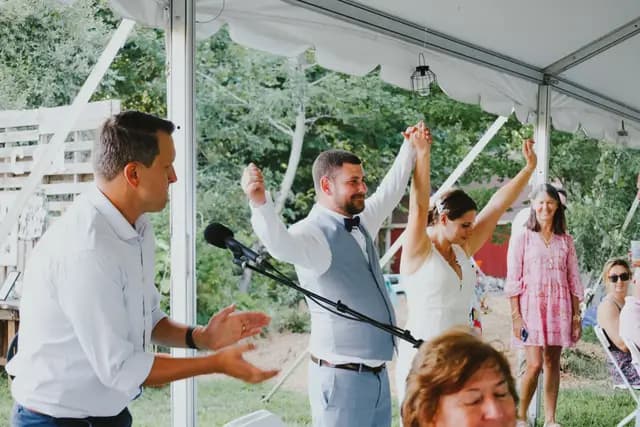 Newlyweds raise their joined hands as they are announced into the reception
