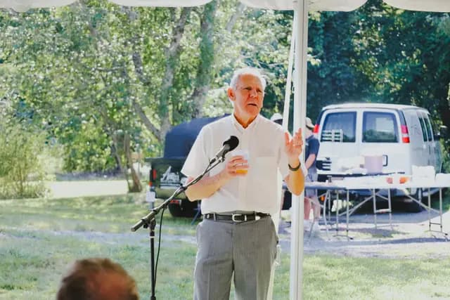 An older guest gives a toast at the microphone during the reception