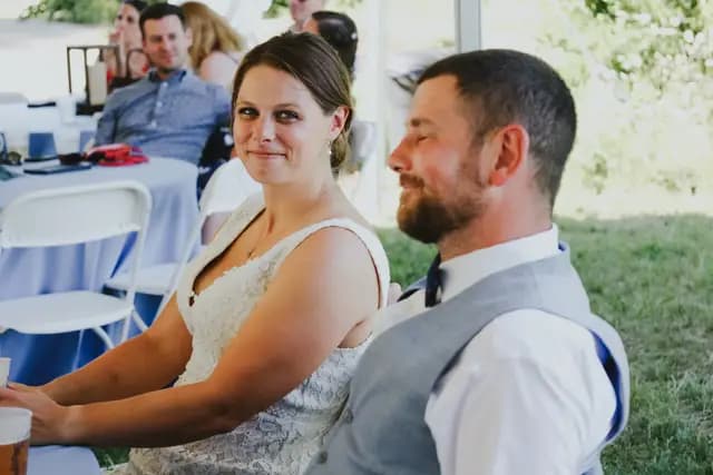 Bride and groom listen to speeches at their reception table