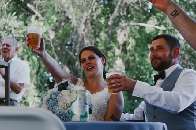 Bride and groom raise their drinks in a toast at the reception