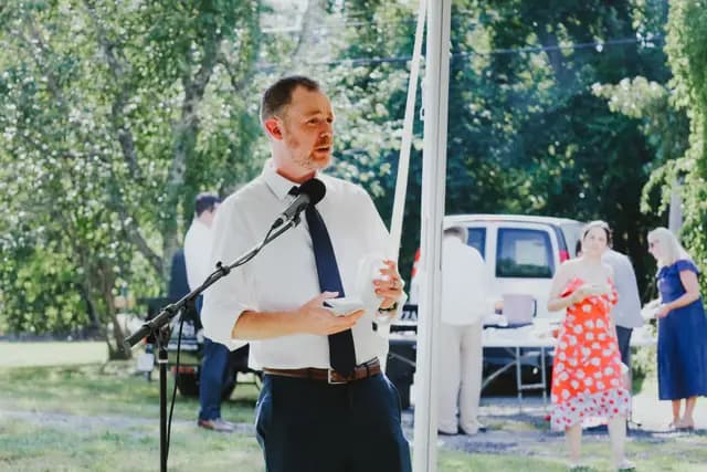 A guest in shirtsleeves gives a toast at the microphone