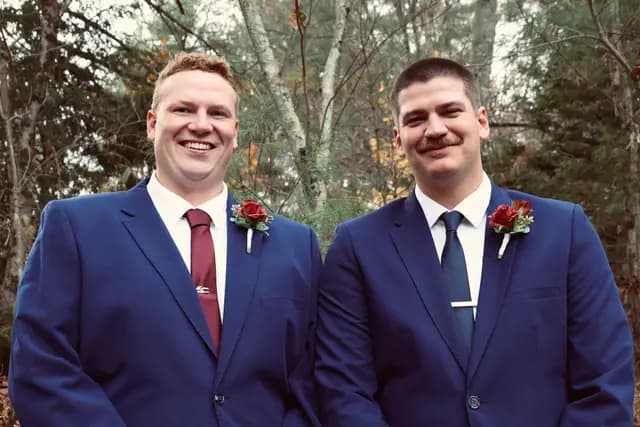 Groom and his best man smile side by side in navy suits