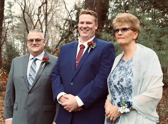 Groom poses with his parents before the ceremony