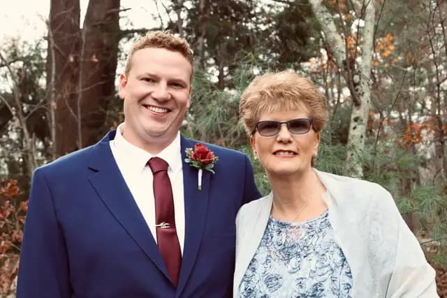 Groom smiles beside his mother in her blue lace dress