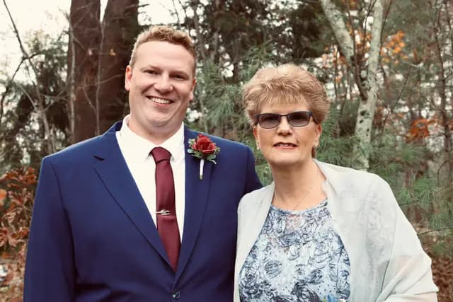 Groom and his mother pose together among the pines