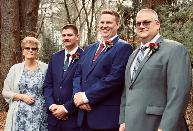 Groom smiles with family before the ceremony in the pines