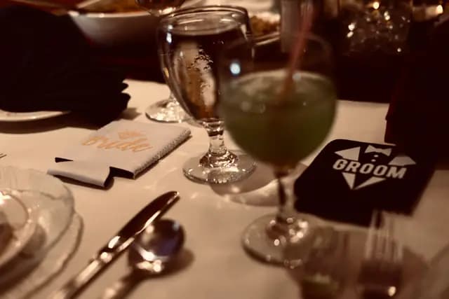 Bride and groom drink koozies beside a green cocktail on the table