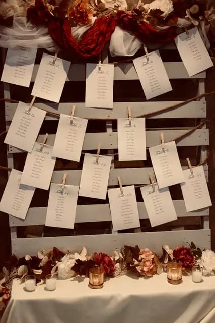 Seating chart cards pinned to a pallet board with autumn florals