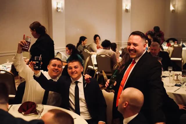 Guests raise their drinks and mug for the camera at the reception