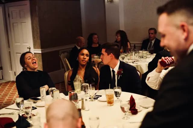 A guest laughs during dinner as friends chat around the table