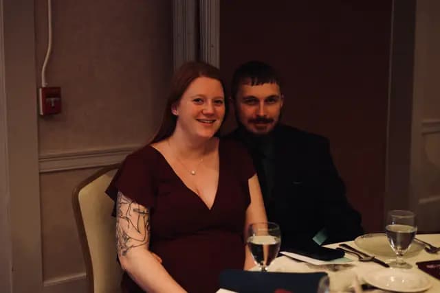 A couple smiles for a photo at their reception table