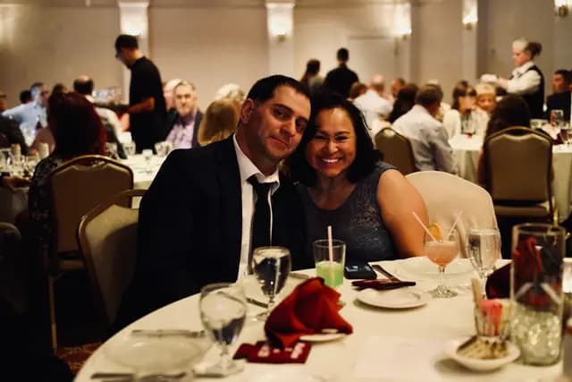 A couple leans in for a photo amid the busy reception