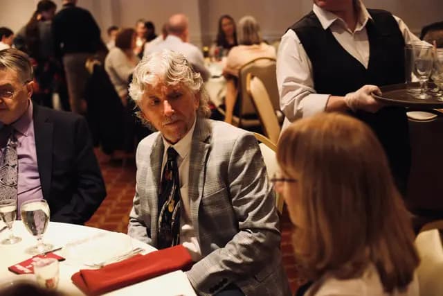Guests chat at their table as a server passes with a tray