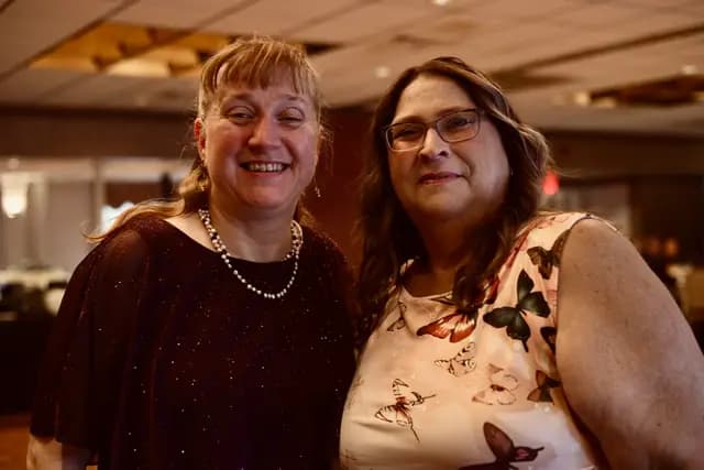 Two guests smile together for a photo at the reception
