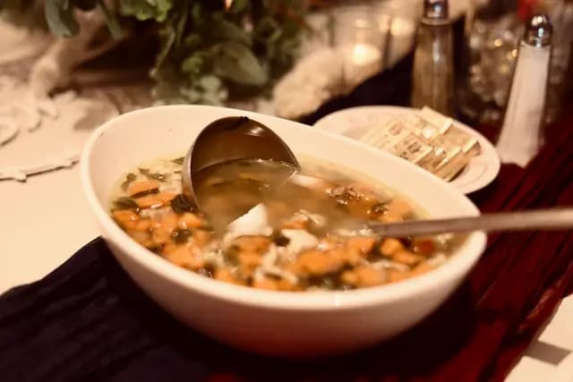 A ladle rests in a serving bowl of Italian wedding soup