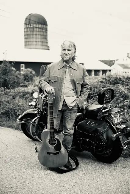 Black and white portrait with guitar and motorcycle by the old silo