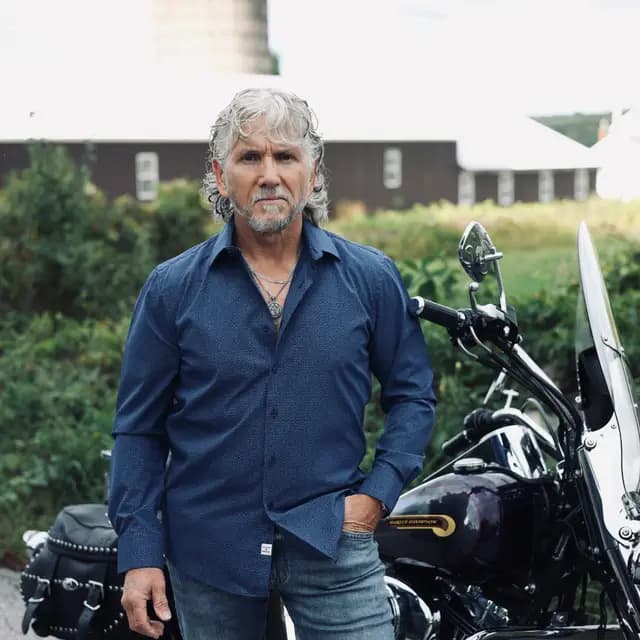 Blue button-down portrait beside the Harley windshield