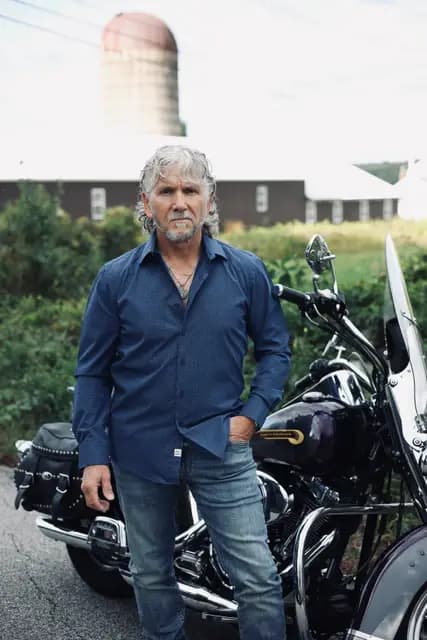 Hands in pockets beside the tank of the Harley