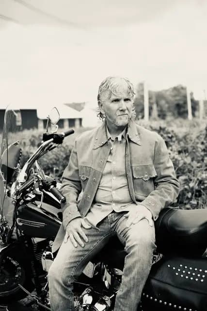 Black and white of the seated pose in the suede jacket