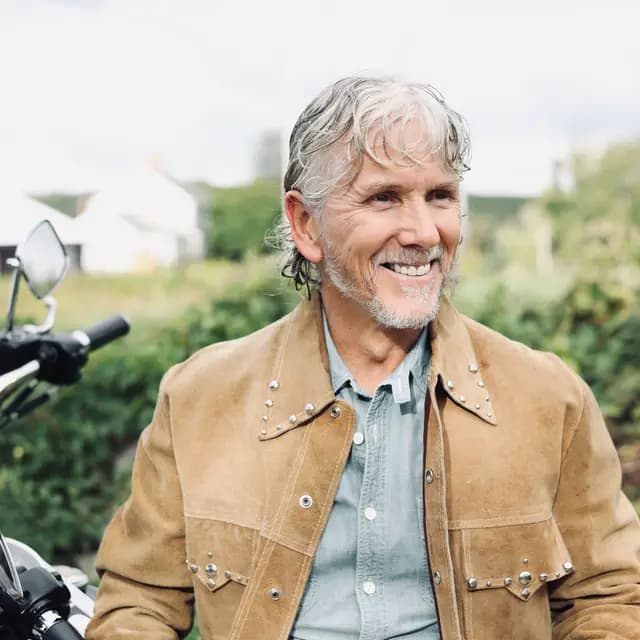Close crop of the artist grinning in the studded suede jacket
