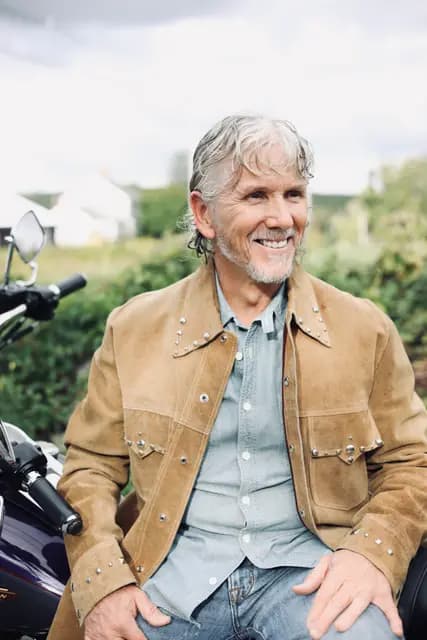 Relaxed smile with hands folded in his lap