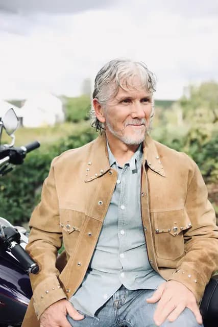Seated with a calm look off camera, suede over chambray