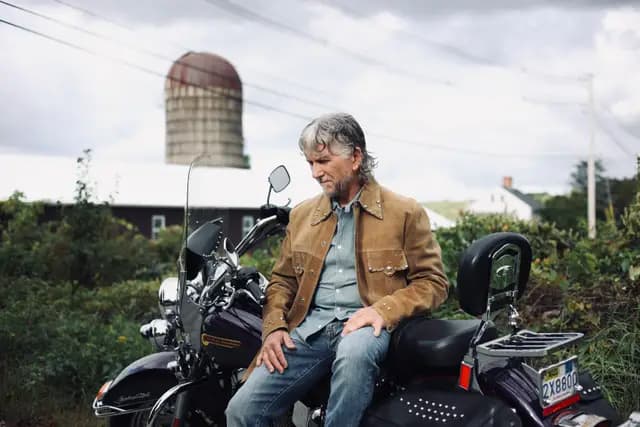 Resting on the Harley under the silo, hand on his knee