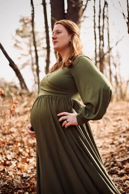 Close profile cradling her bump in warm afternoon light
