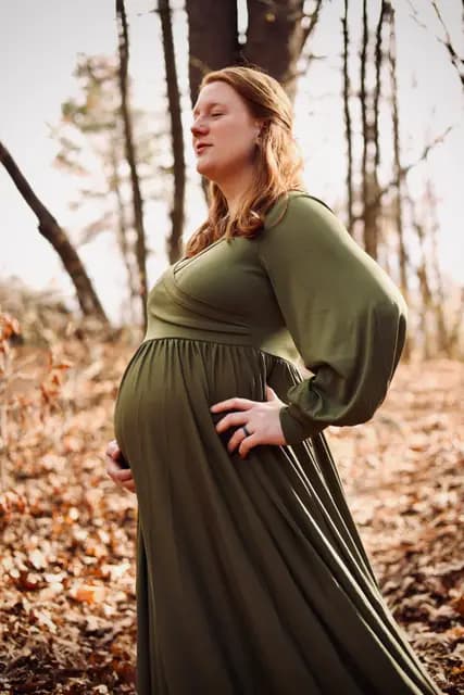 Eyes closed to the sun, hands resting on her belly