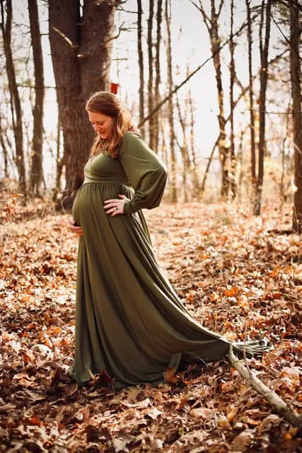 A soft smile down at her bump as the gown pools over the leaves