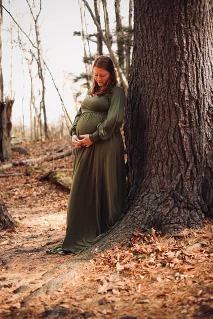 A quiet moment against the big oak, eyes on her belly