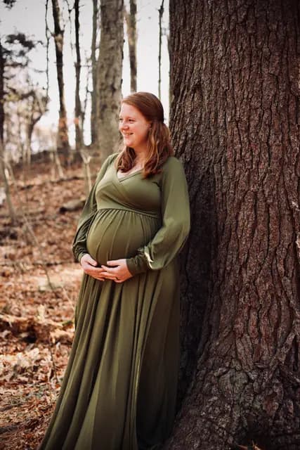 A smile off into the woods while resting against the big tree
