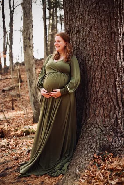 A bright smile from the tree line, hands wrapped around the bump
