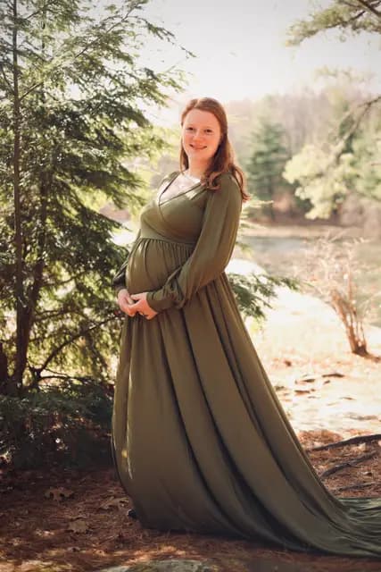 The olive gown trails past the evergreens by the pond